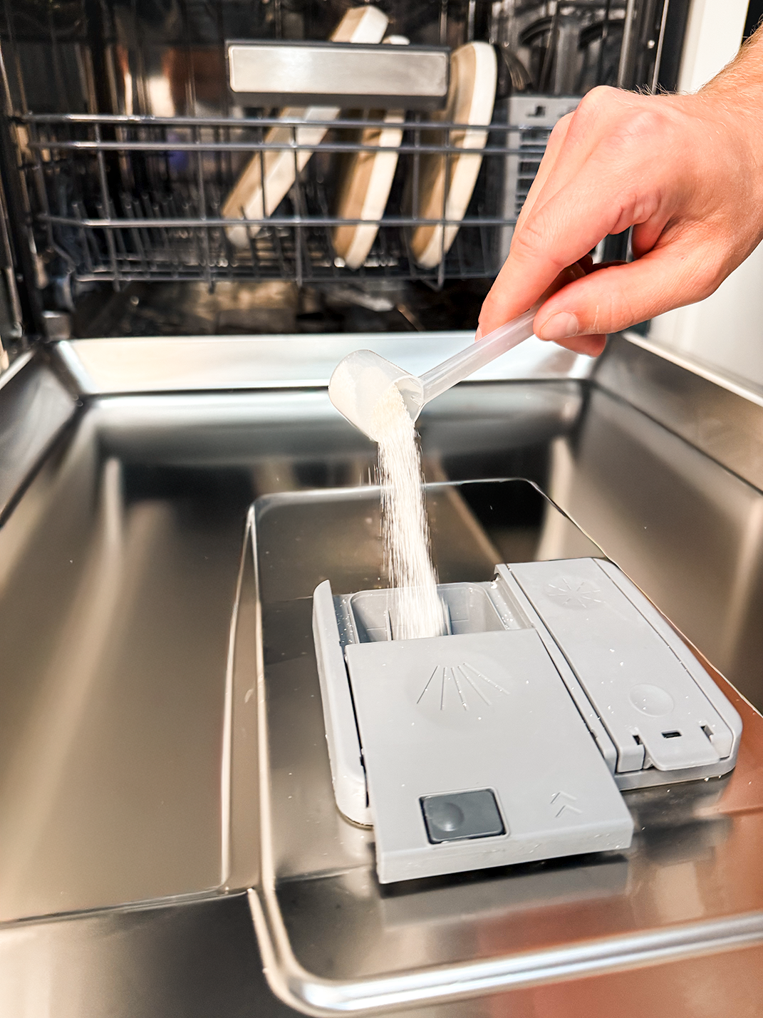Adding dishwasher powder to the detergent compartment before starting a wash cycle